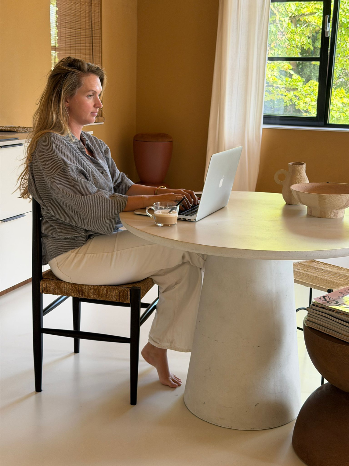 Britt werkt met haar laptop aan de ronde eettafel in de studio van Casa Momo